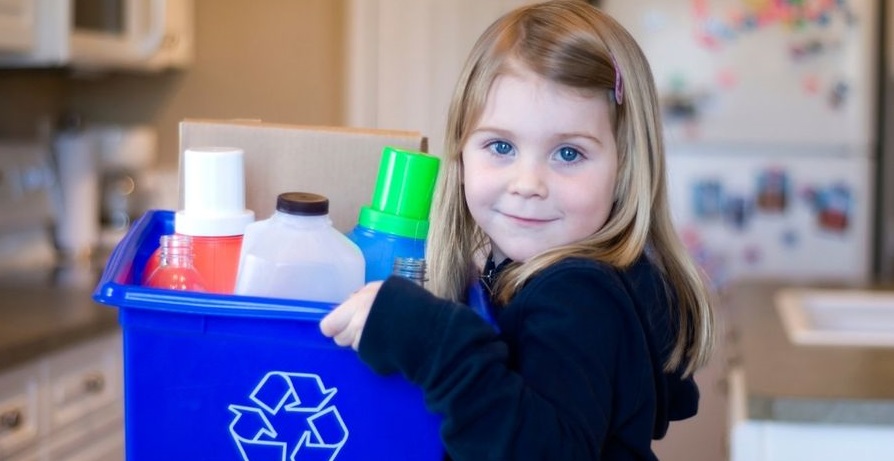 A child holding a recycling box full of plastic containers.